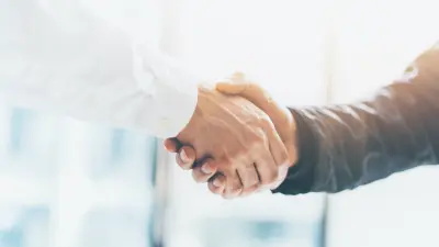 Close up two men shaking hands with bright light coming from behind